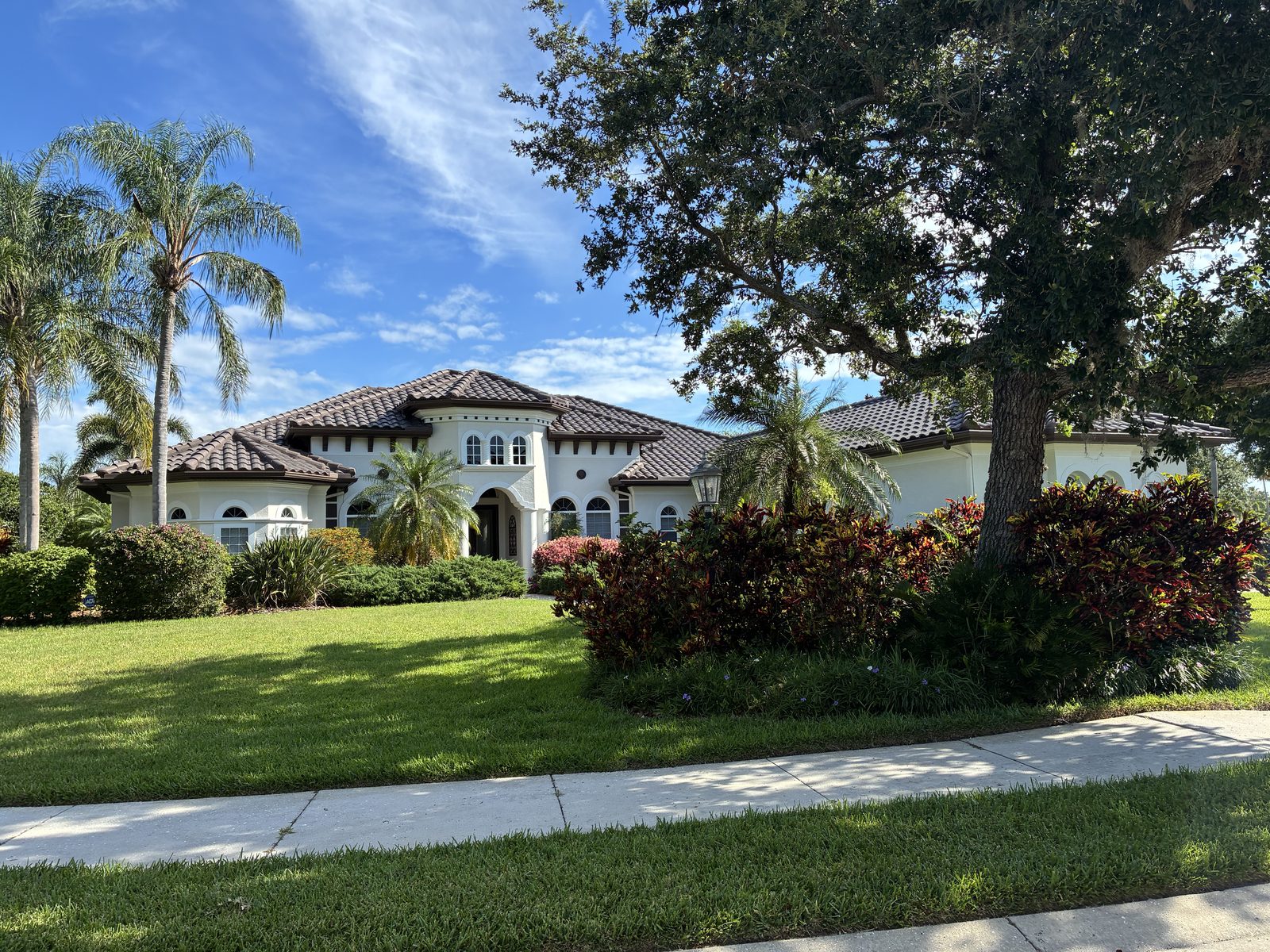 Grand two-story white Mediterranean home with a tile roof and mature palms