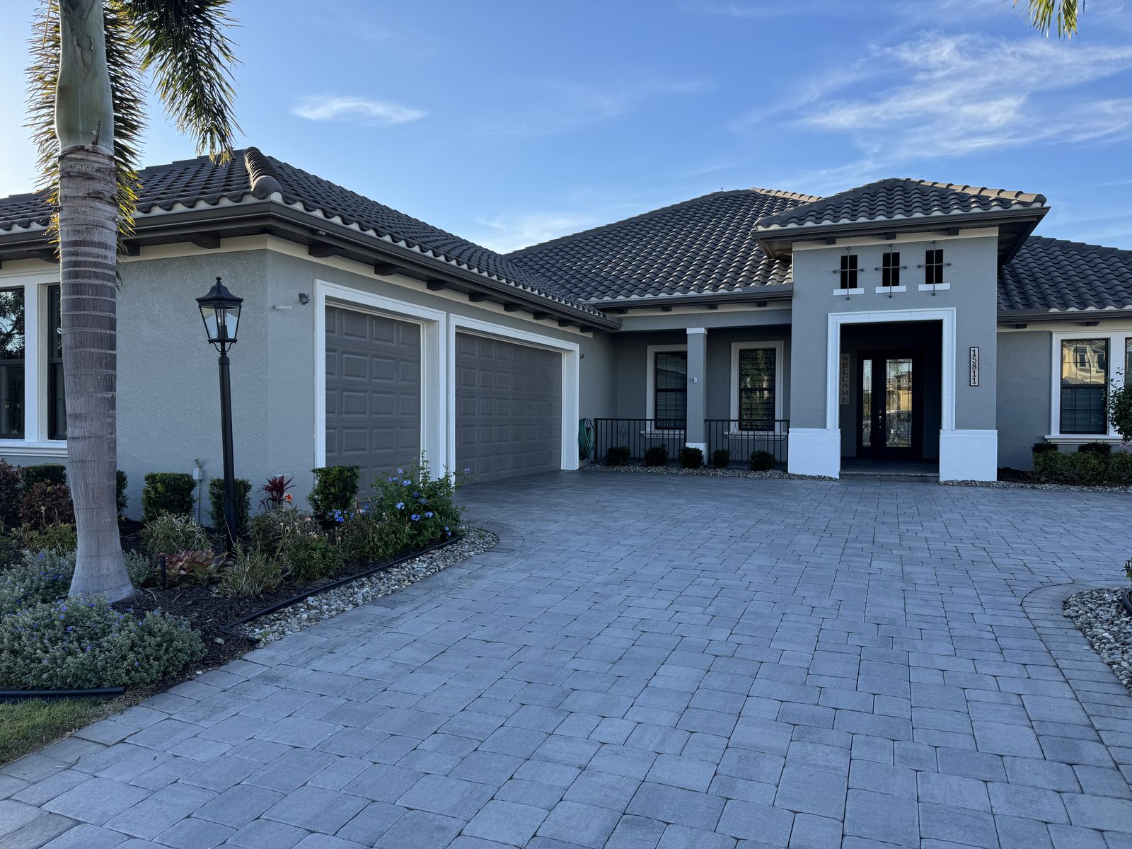 Single-story Florida home with soft gray stucco, white trim, and a barrel-tile roof, freshly painted