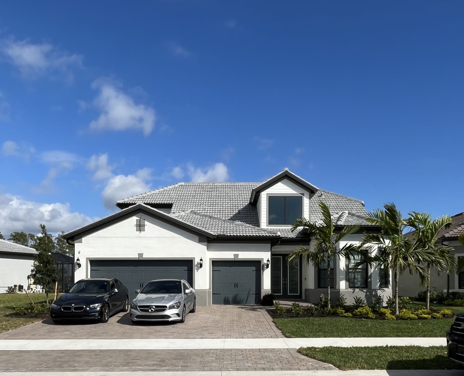 Freshly painted large two-story white Florida home with a three-car garage and paver driveway